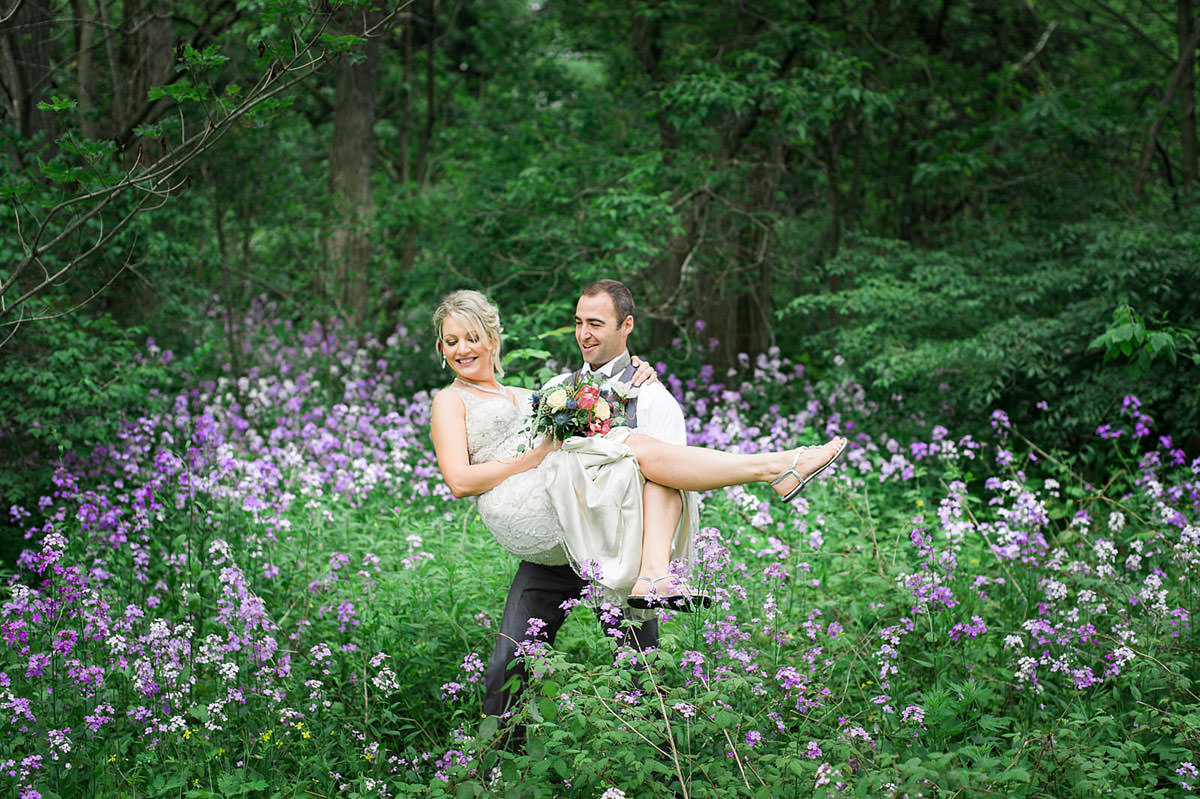 groom carries bride over lavender field