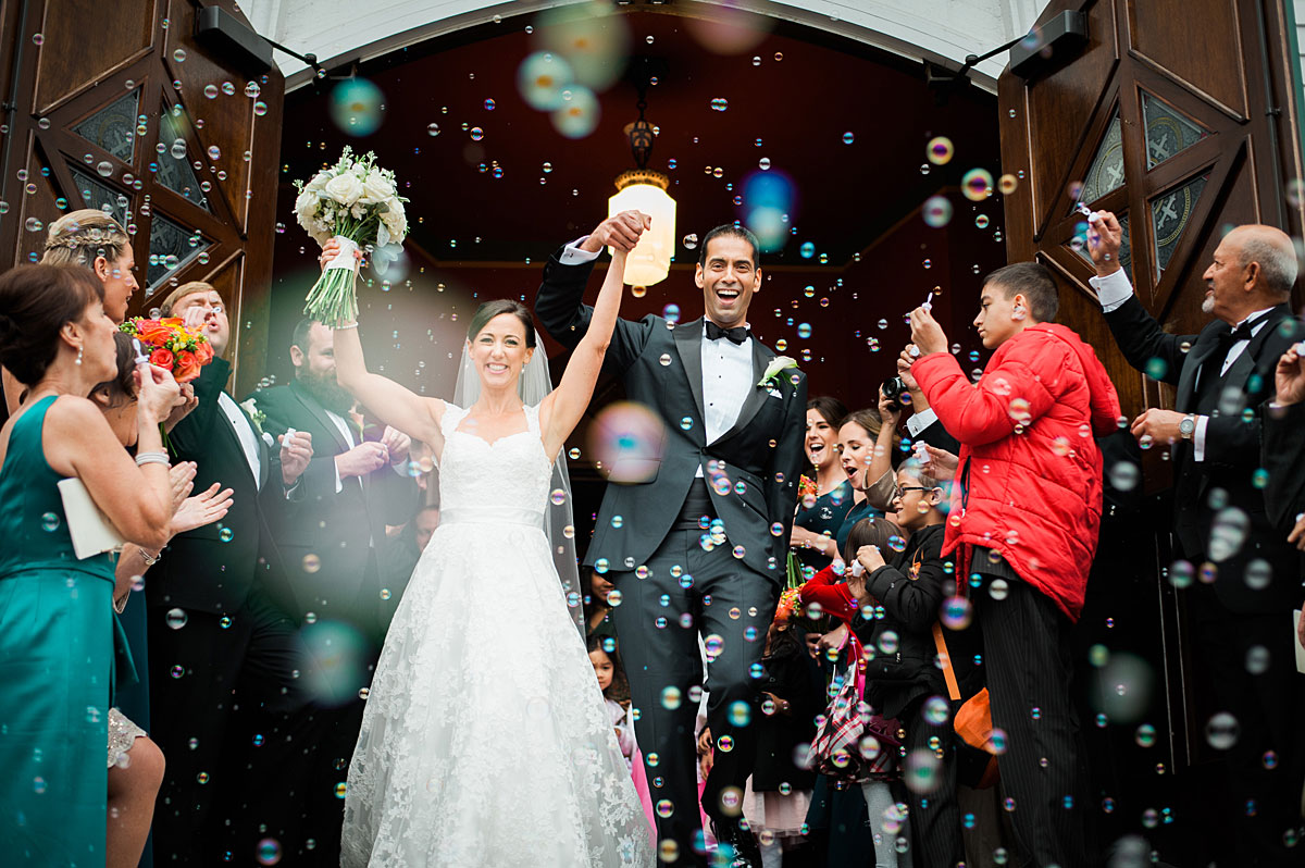 Wedding couple leaving their church ceremony with bubbles